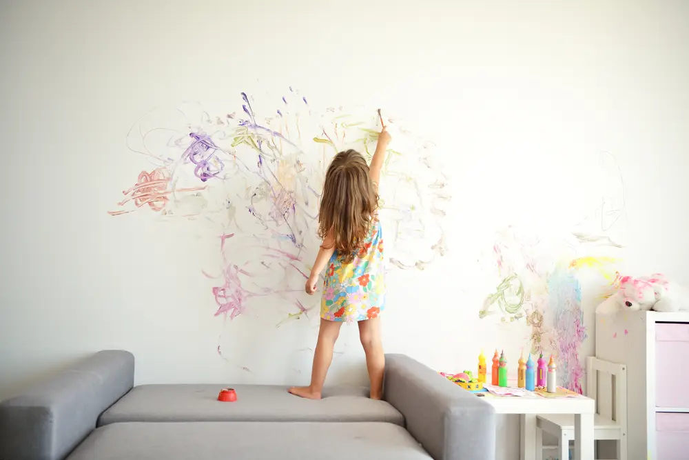 toddler drawing on the walls as they play at home in their daily routine 