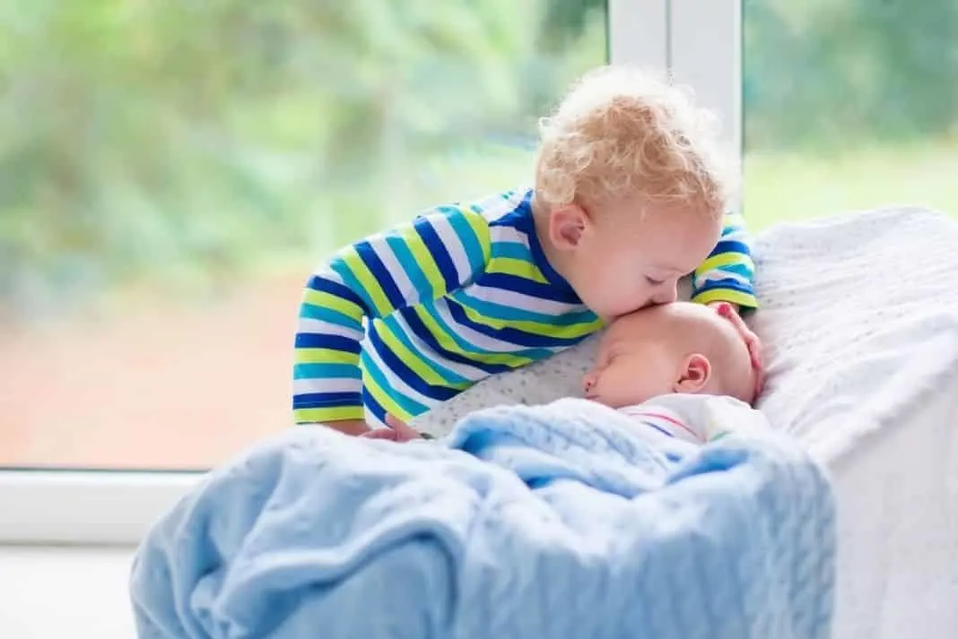 Sibling kisses second baby on the head 