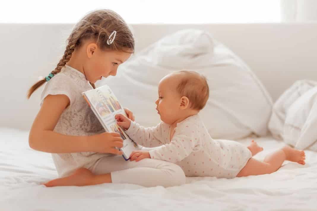 Big sister reading with newborn baby sibling 