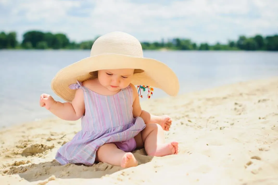 Baby girl wearing hat by the water 